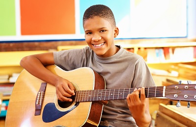 child with a smile holding a
guitar